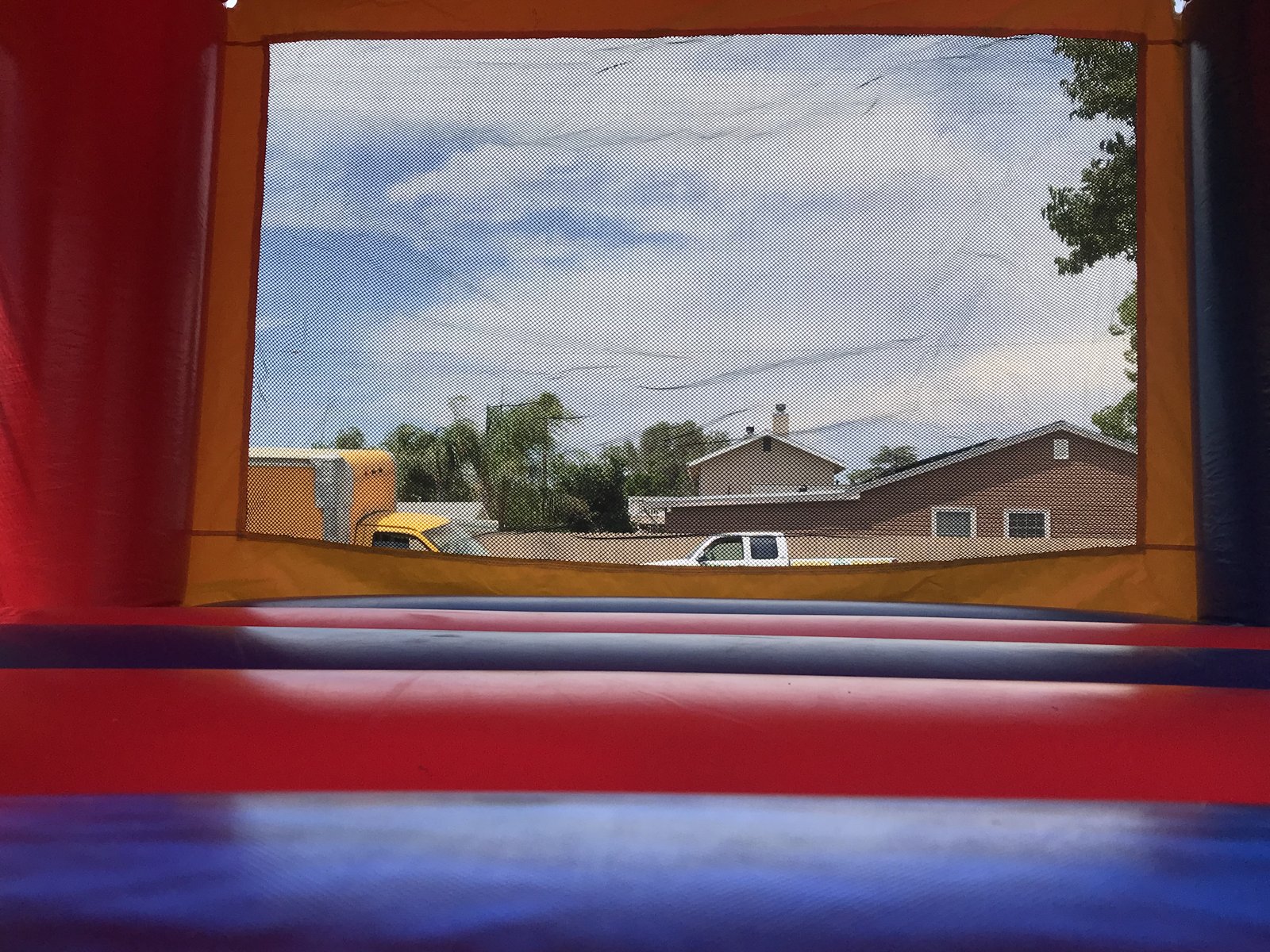 13x13 Multi-Color Castle bounce house rental in San Diego — inside view of the red and blue jumping floor looking out the large mesh safety window