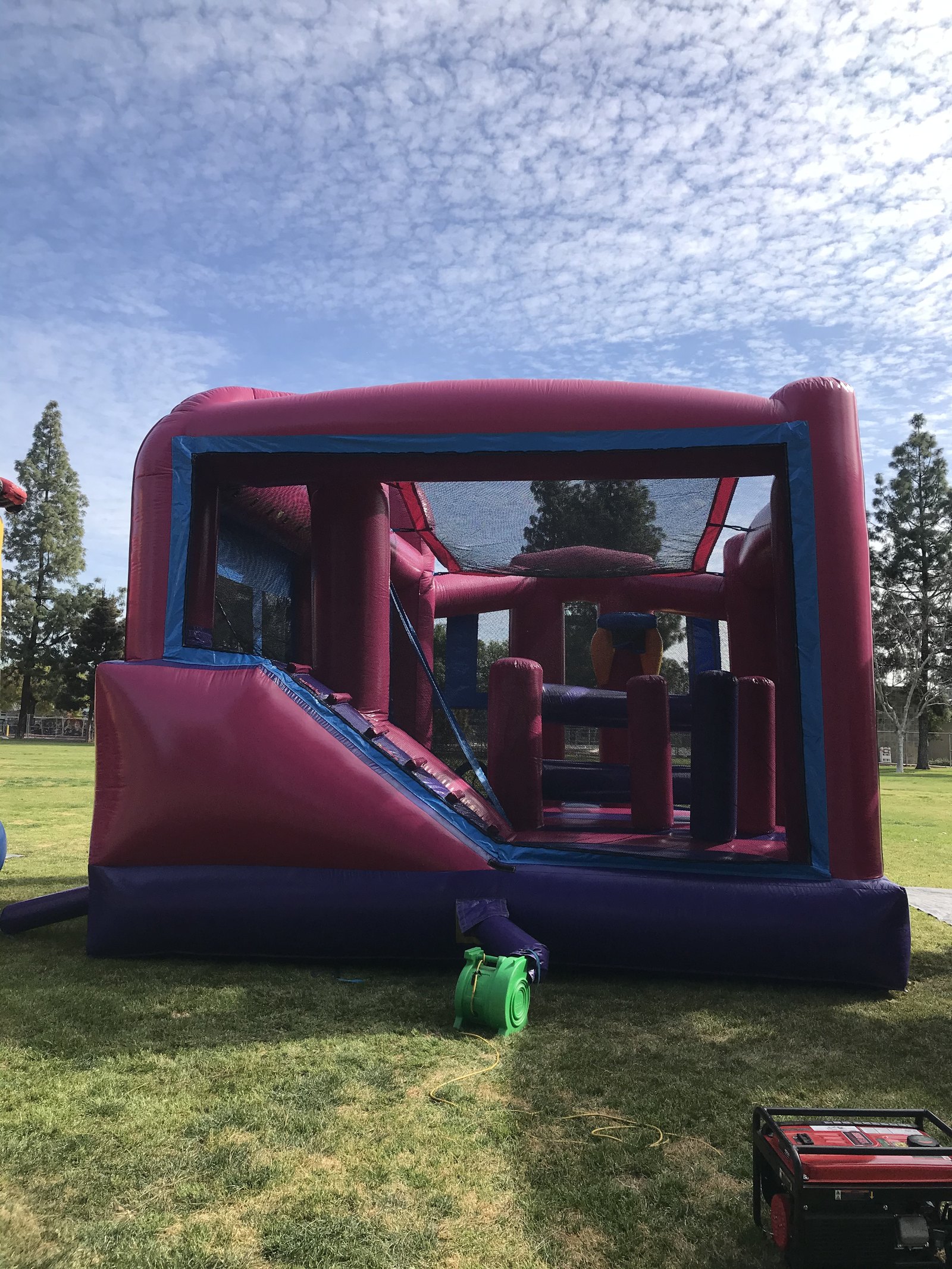 5n1 pink banner combo bounce house rental in San Diego, straight-on front view with the blower and generator set up on grass