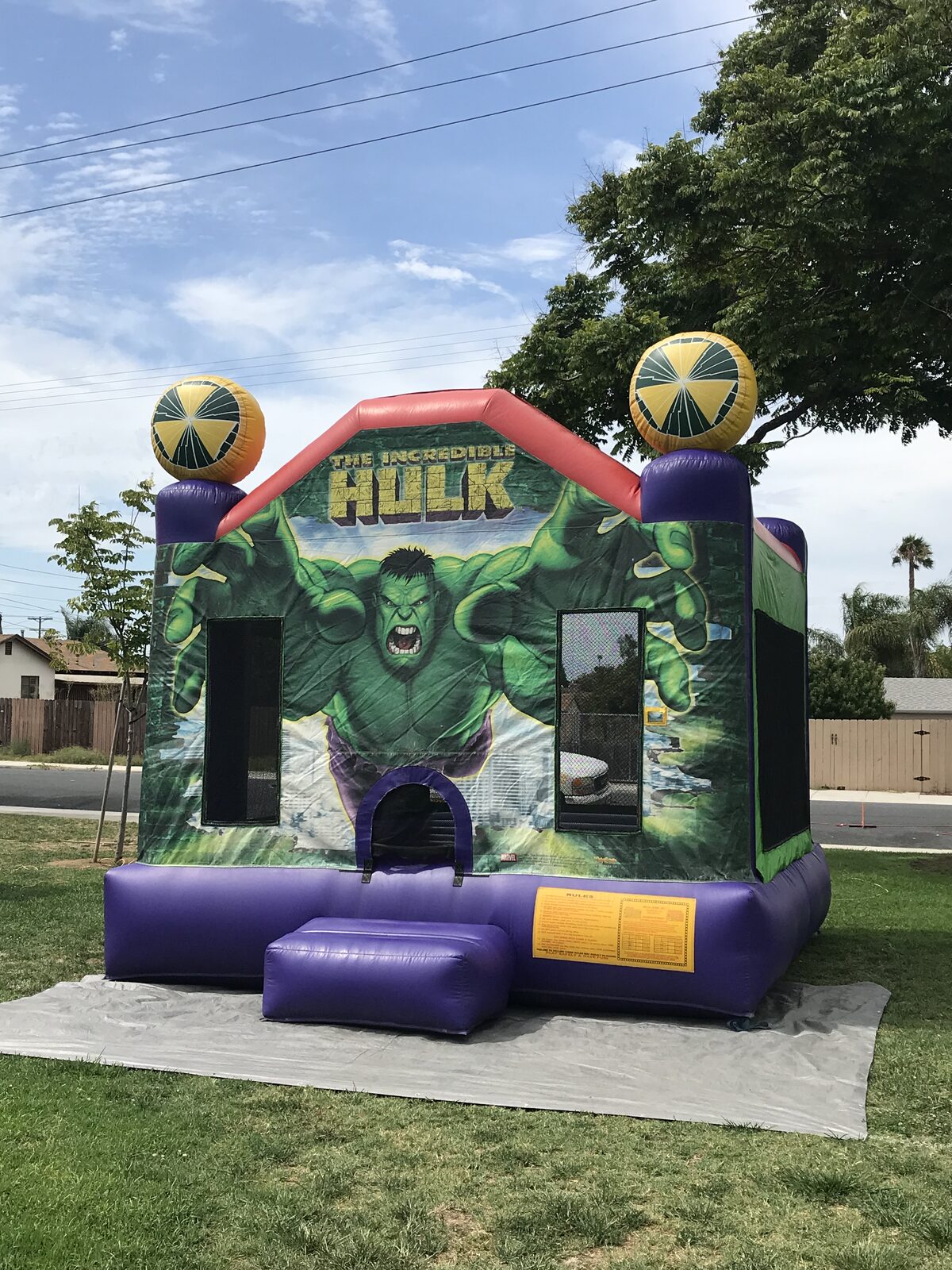 13x13 Incredible Hulk bounce house rental in San Diego — angled view set up on a grass lawn over a protective tarp