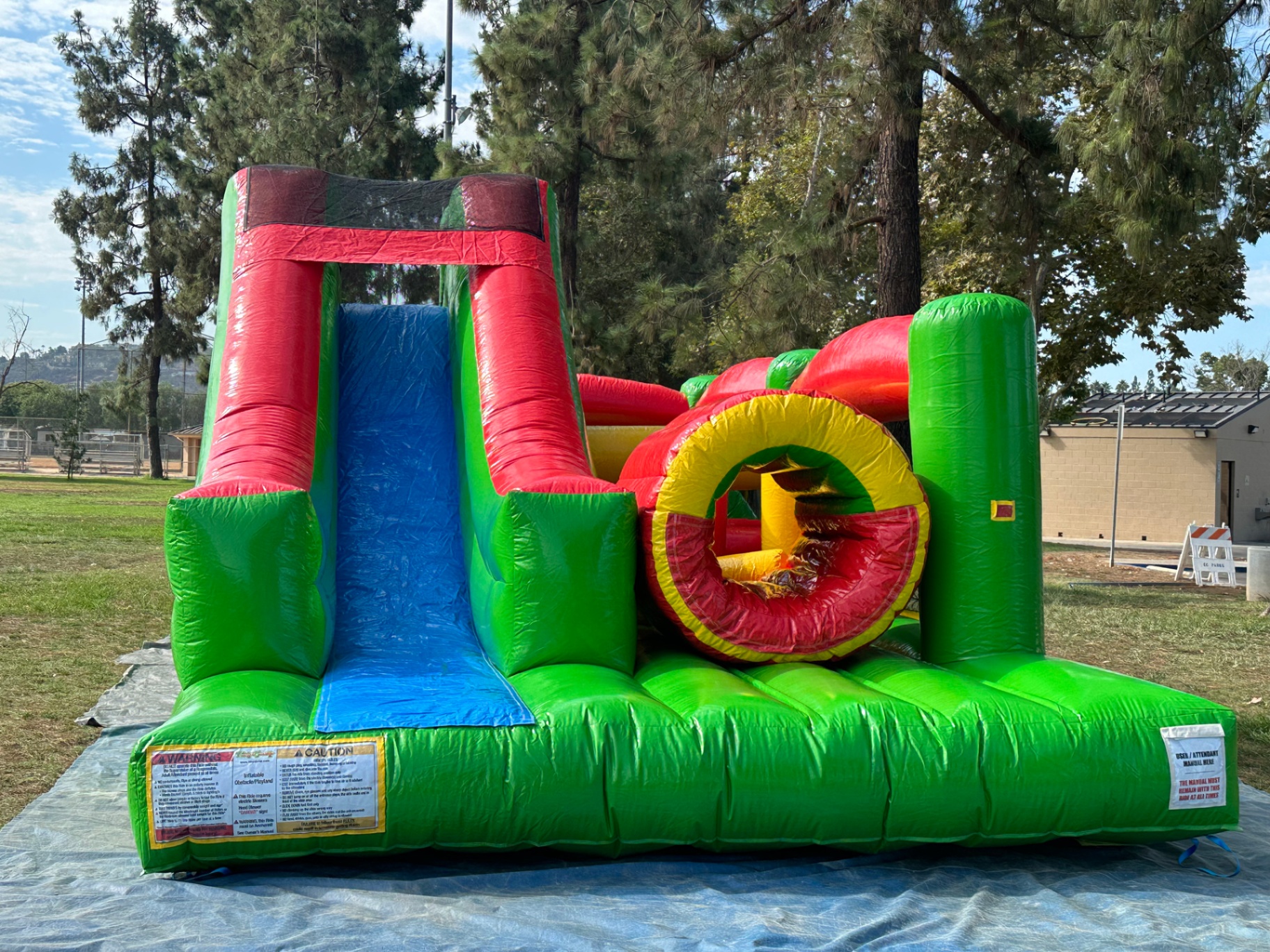 Challenge course obstacle rental in San Diego, green and red lane, front view showing the slide lane and safety warning panels