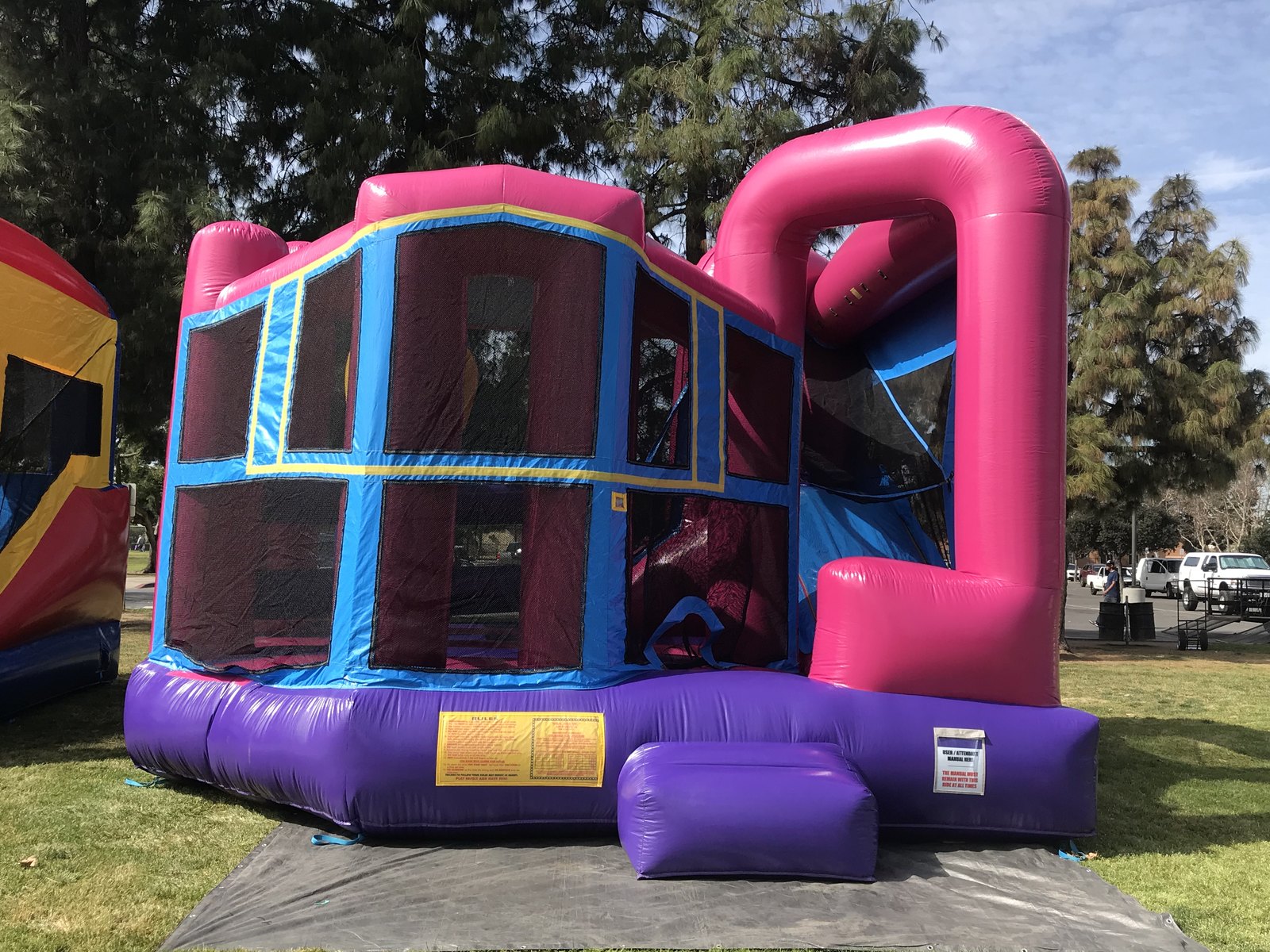 5n1 pink banner combo bounce house rental in San Diego, close side view showing the yellow-trimmed panels and safety rules placard