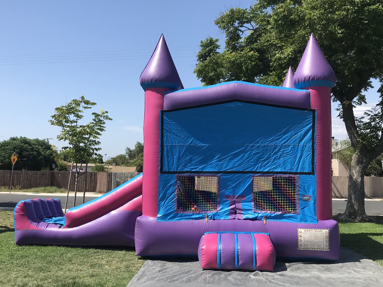 2n1 pink castle banner combo bounce house rental in San Diego, front view of the pink and purple castle with blue banner panel and side slide