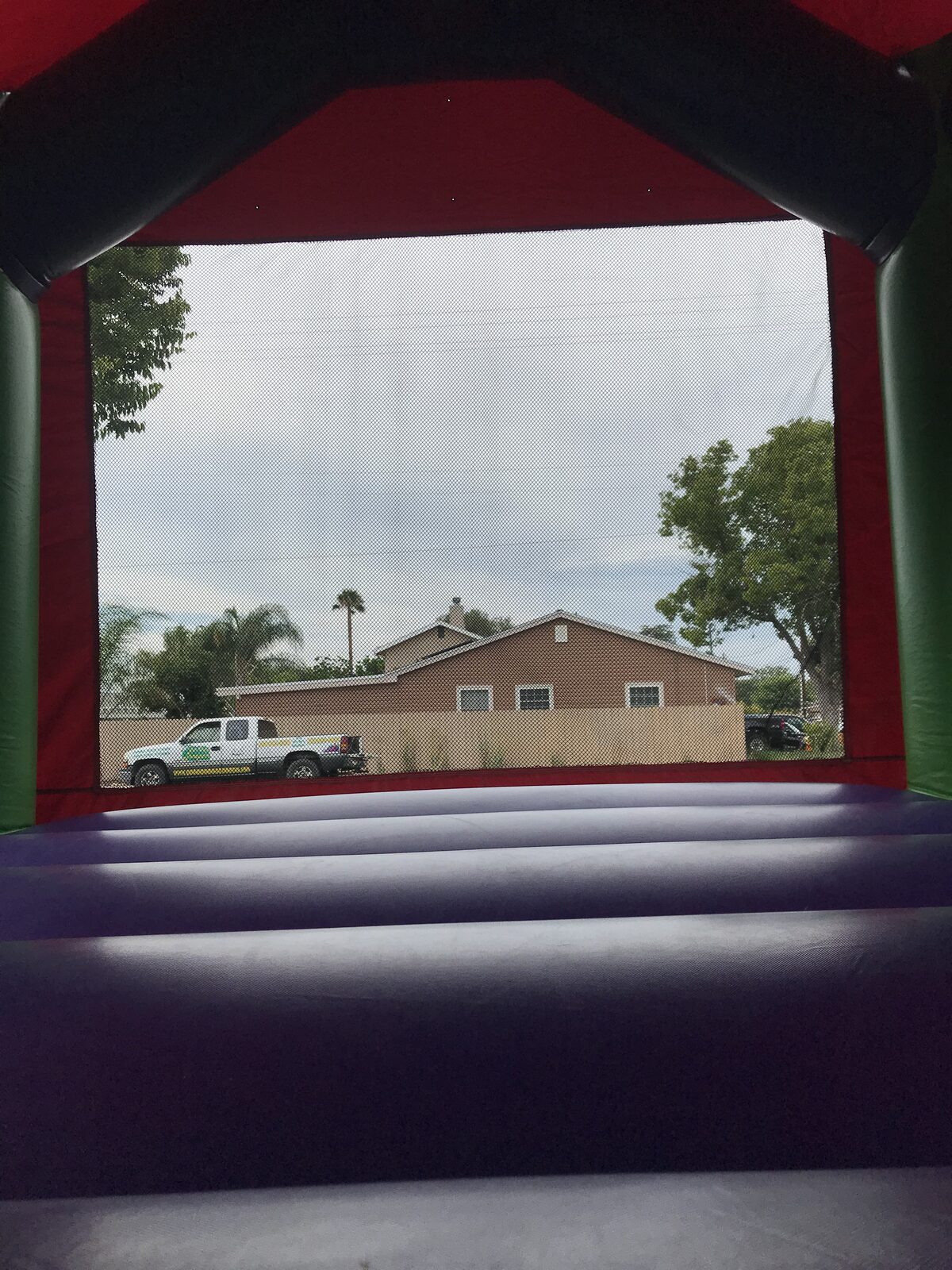 13x13 Ariel bounce house rental in San Diego — inside view of the purple jumping floor looking out the large mesh window
