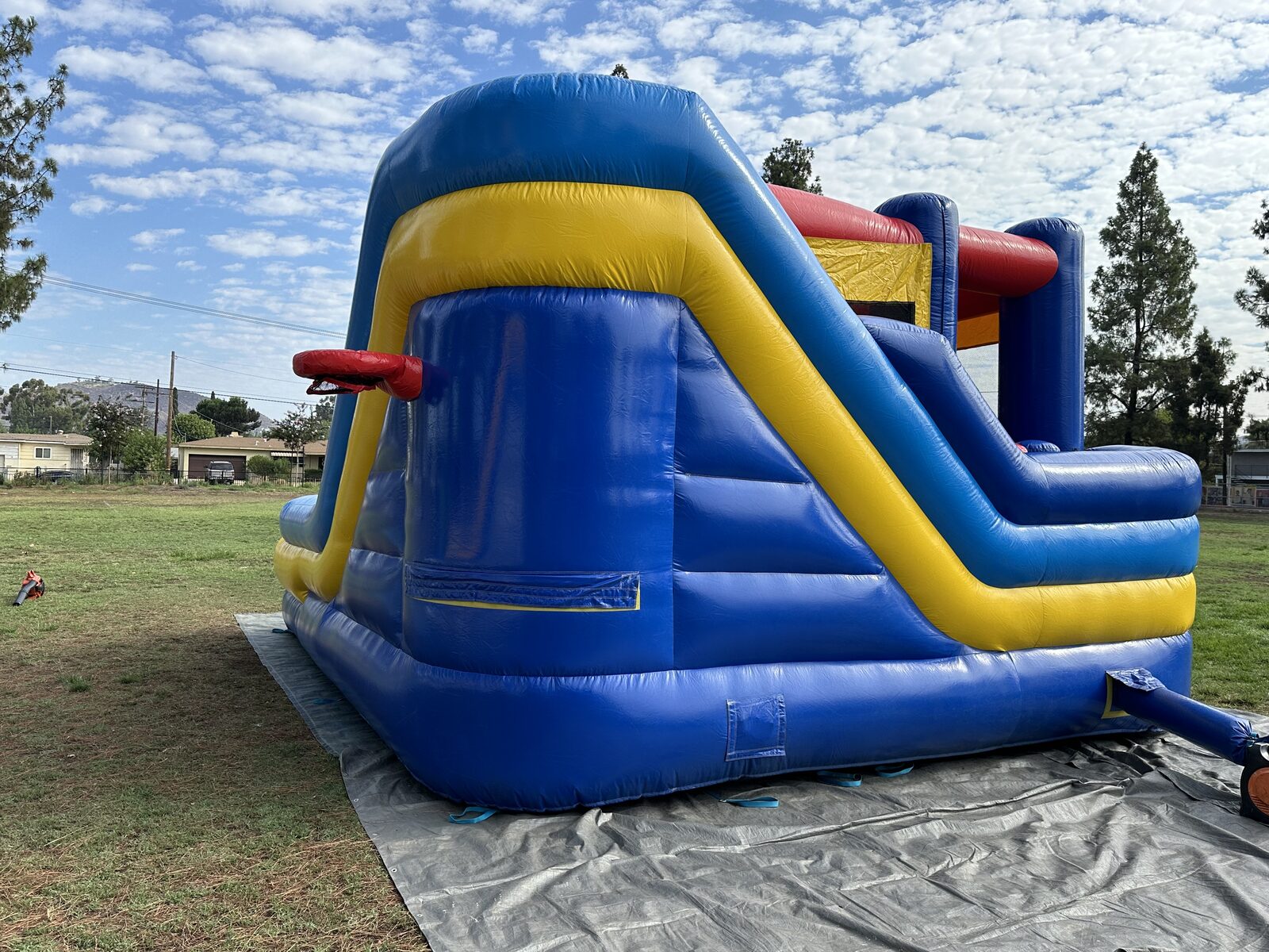 6n1 blue castle banner combo bounce house rental in San Diego, side view of the blue and yellow slide lane with the exterior basketball hoop
