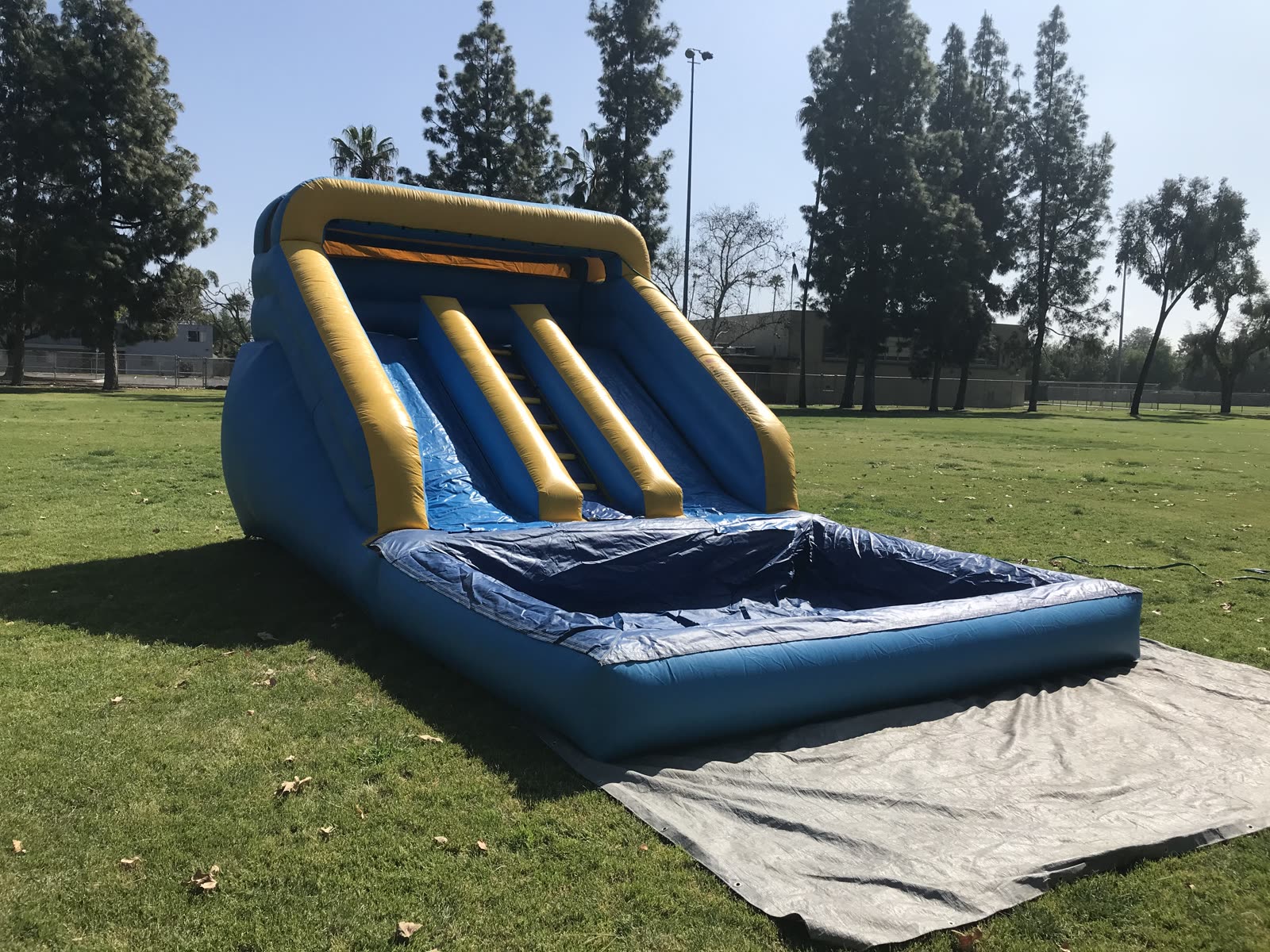 Mini water slide rental in San Diego, 12ft mini dual lane slide angled view on grass showing the low slide height for younger kids