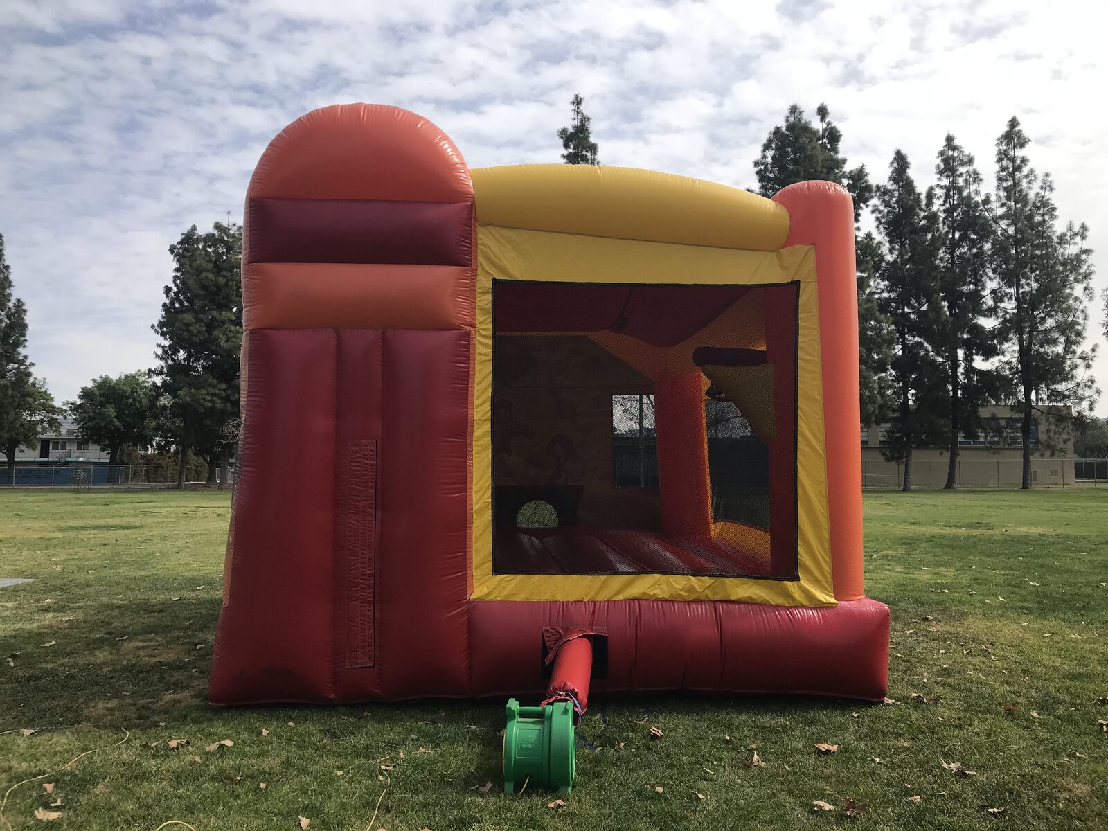 4n1 fairies combo bounce house rental in San Diego, back view of the red and yellow slide tower with the blower hooked up on the field