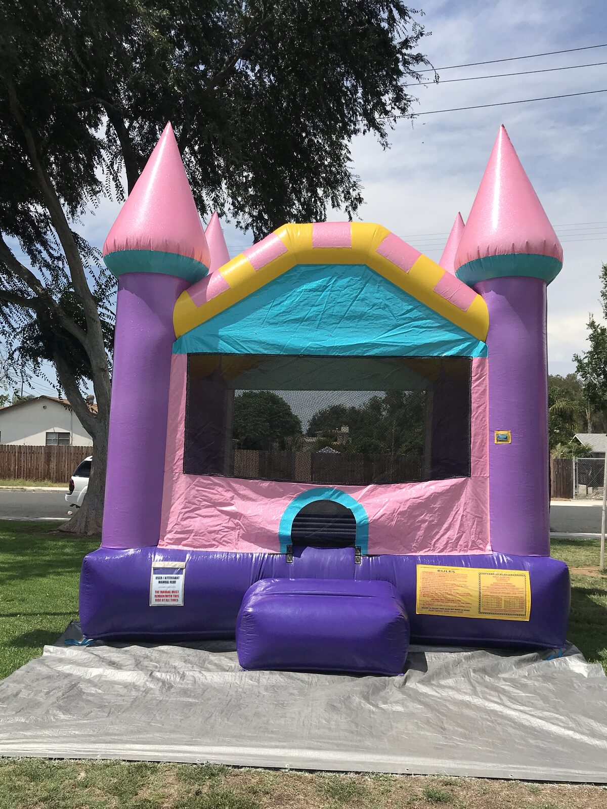 13x13 Dazzling Castle bounce house rental in San Diego — front view with pink glitter turrets, purple columns, and teal and yellow trim