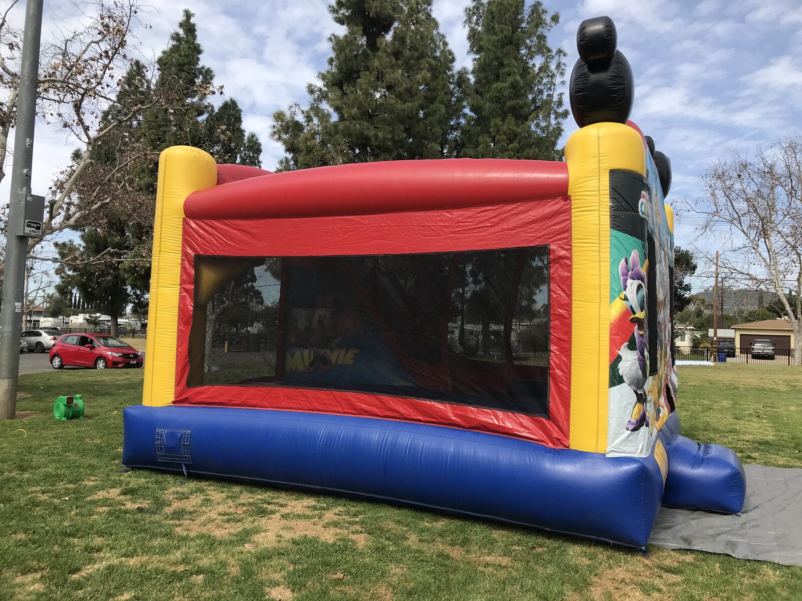 4n1 Mickey combo bounce house rental in San Diego, side view of the red, yellow, and blue unit with full-length mesh safety window