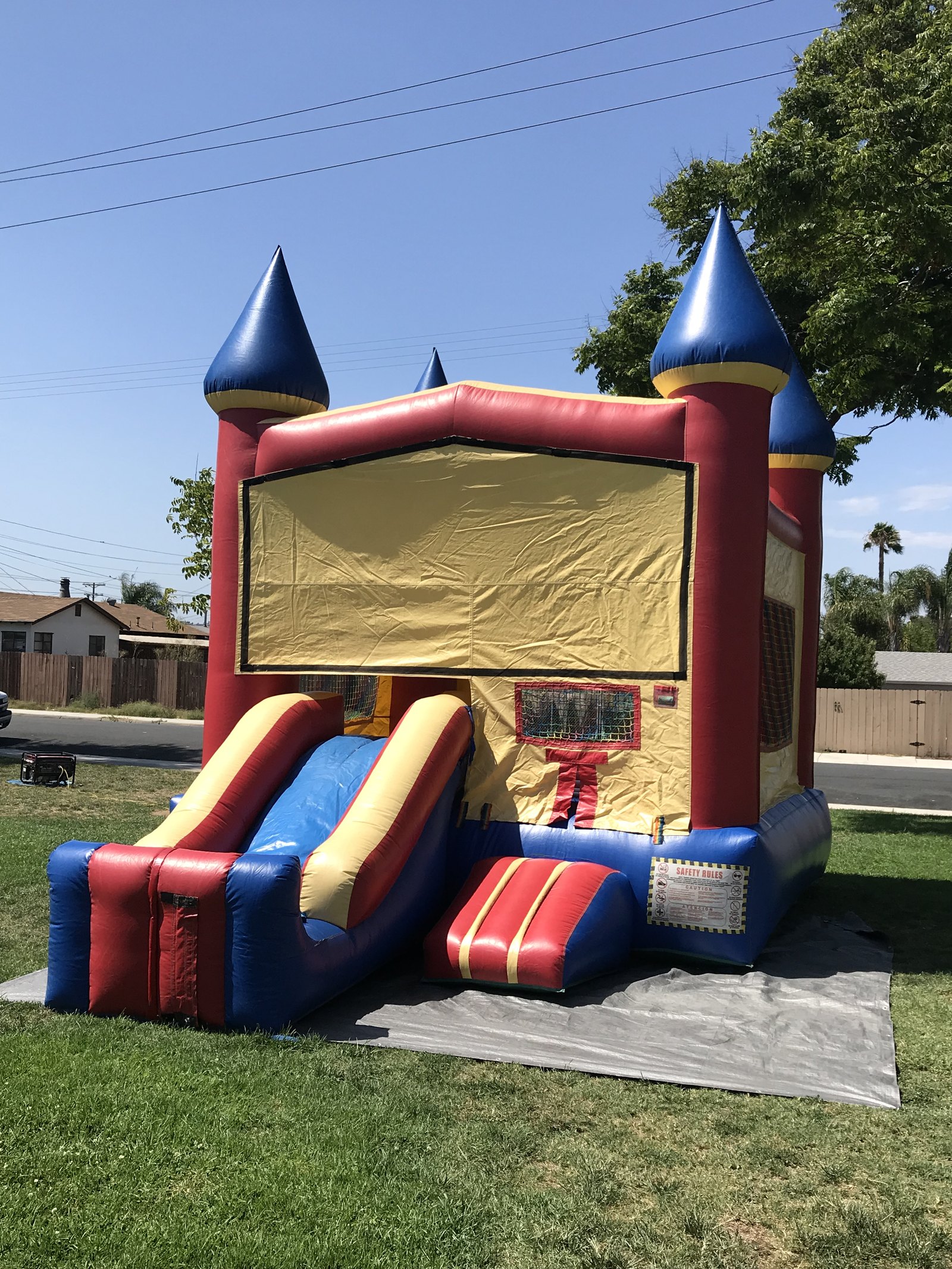 2n1 blue castle combo bounce house rental in San Diego, angled side view showing the full slide run and blower setup