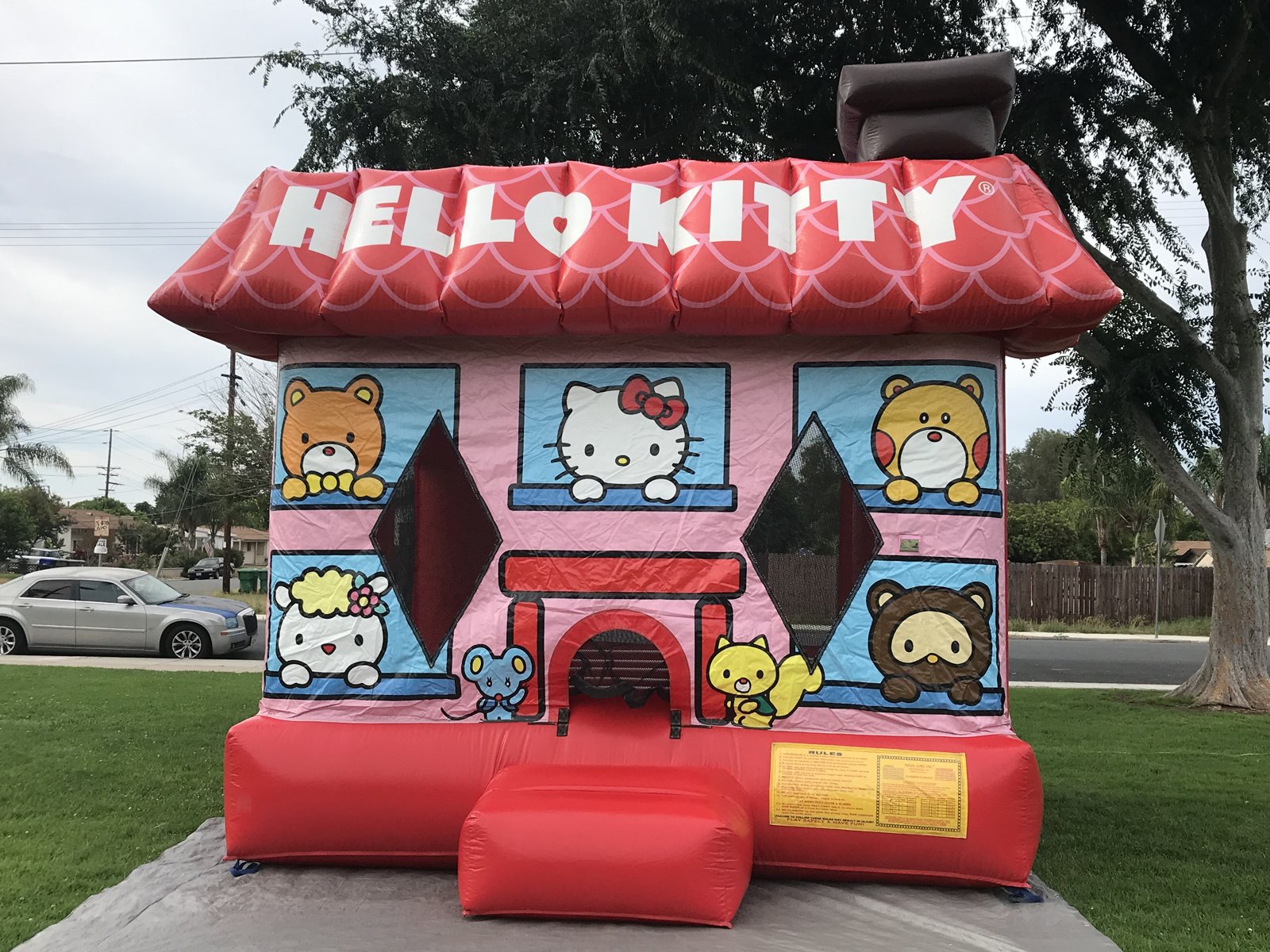 13x13 Hello Kitty bounce house rental in San Diego — straight-on front view of the pink house with red scalloped roof and Sanrio character panels
