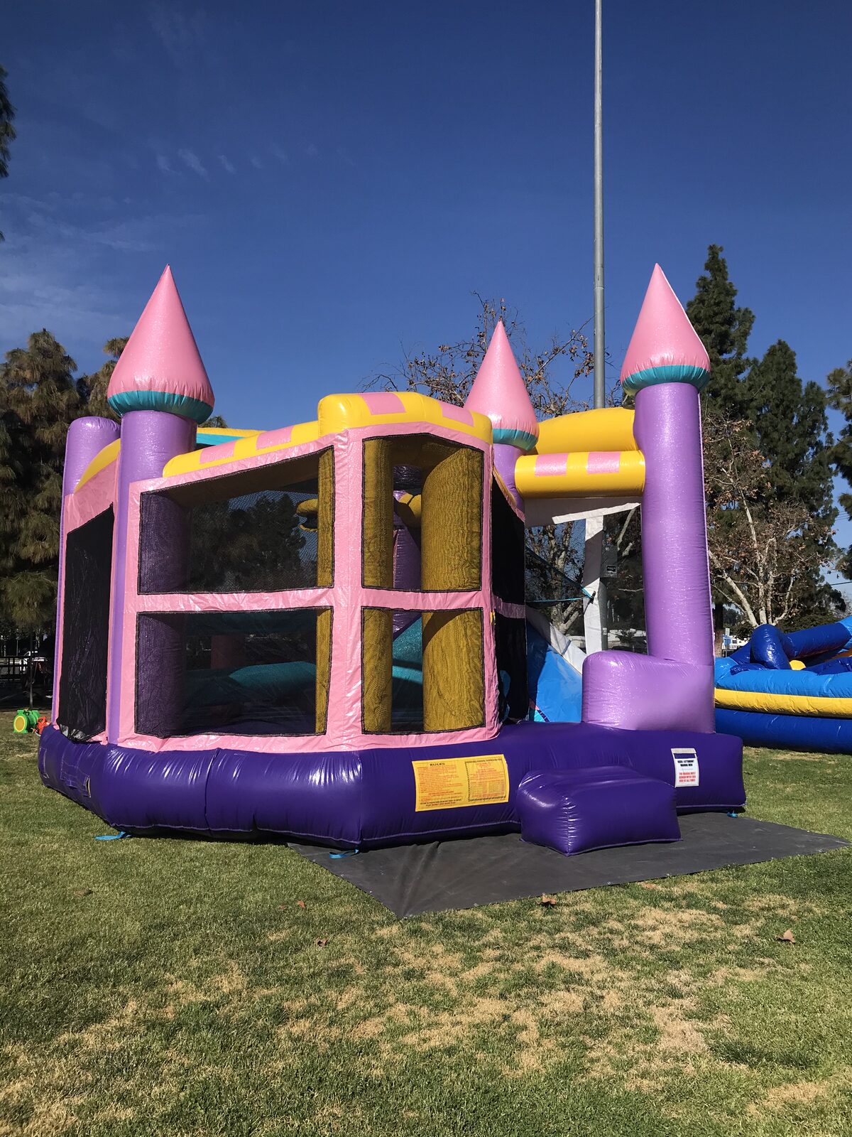 5n1 dazzling castle combo bounce house rental in San Diego, angled front view of the mesh windows and purple entry step