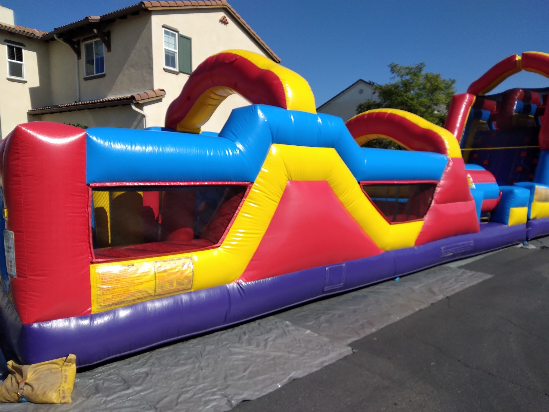 70ft monster obstacle course rental in San Diego, mid-section side view of the arches and mesh windows with the climb wall behind