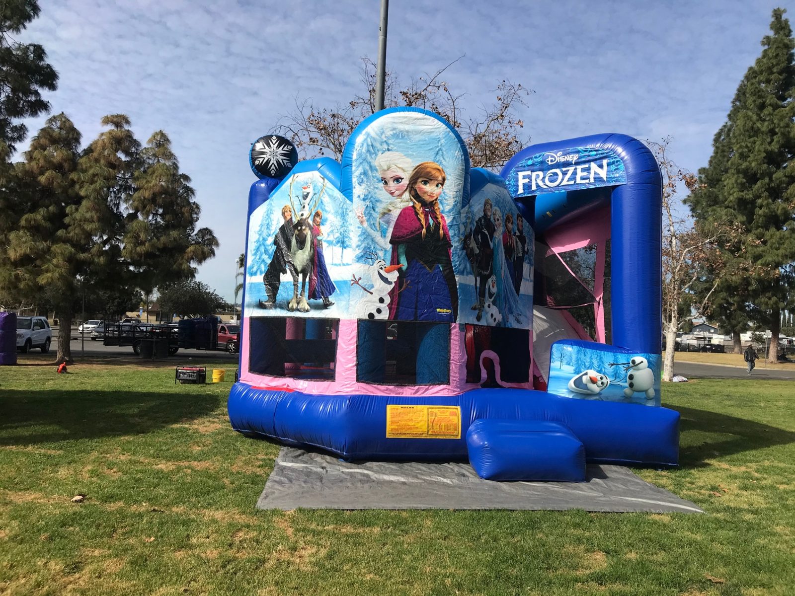 5n1 frozen combo bounce house rental in San Diego, front view of the Elsa and Anna panels with the Disney Frozen slide arch on a tarp at a park