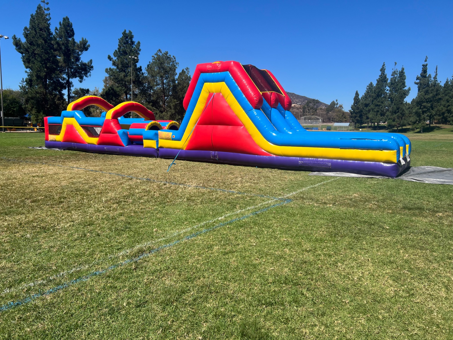 70ft monster obstacle course rental in San Diego, wide side view of the tunnels, arches, and slide exit
