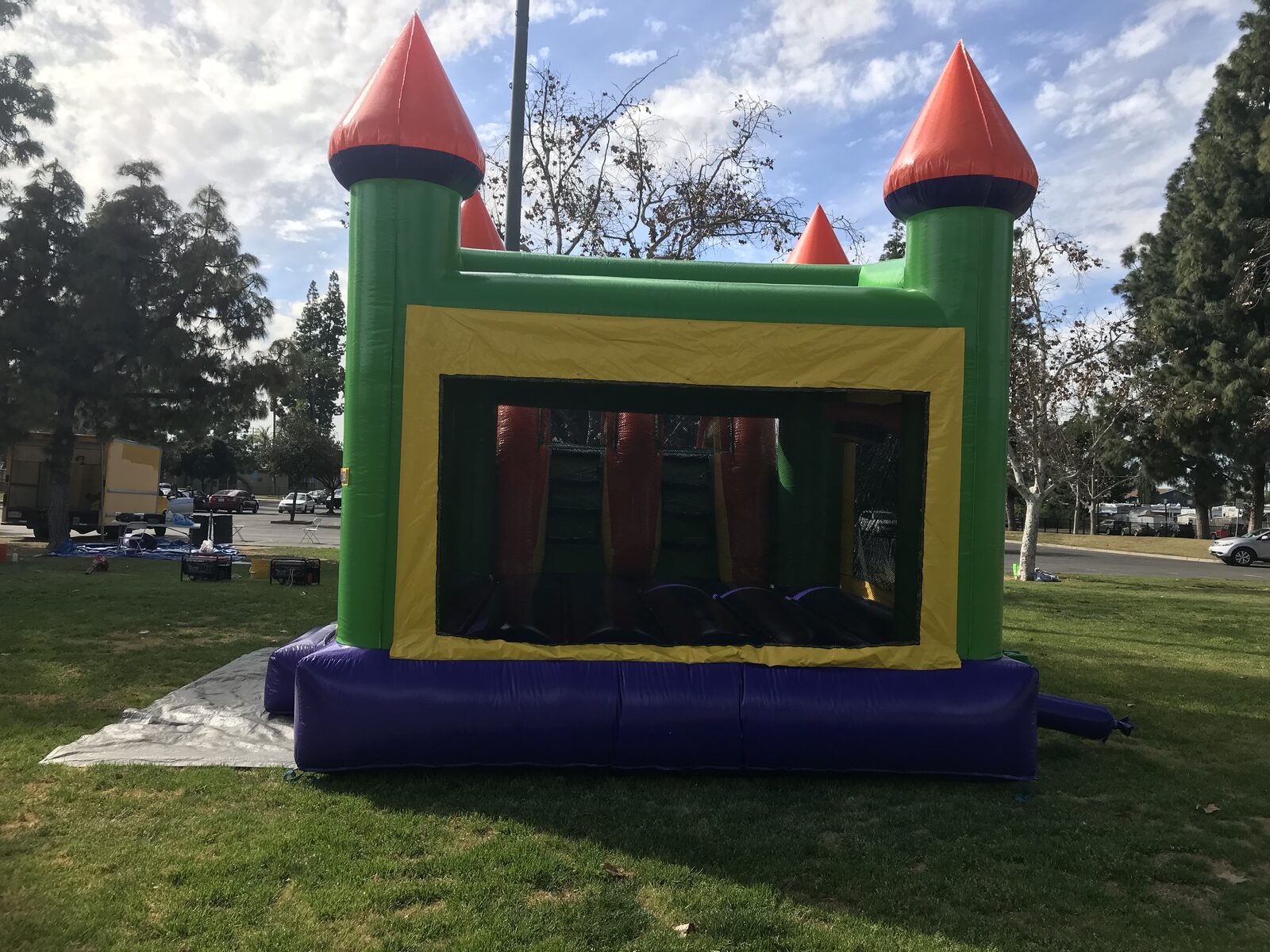 4n1 multi-color castle banner combo bounce house rental in San Diego, side view of the green and yellow banner panel with the large mesh window into the jump area