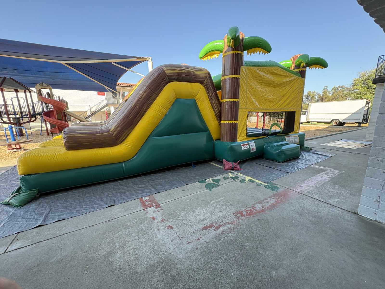 4n1 tropical oasis dual slide combo bounce house rental in San Diego, angled side view of the slide climb and green base