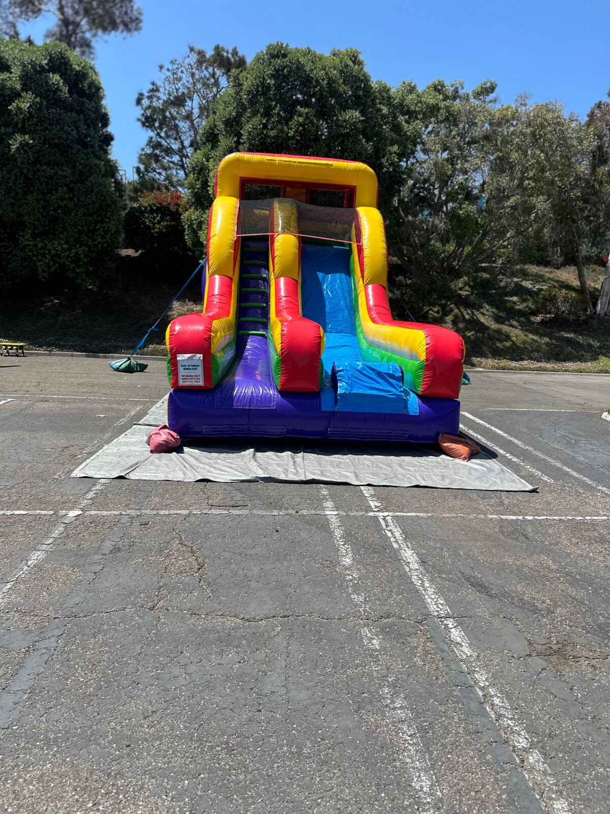 Dry slide rental in San Diego, 15ft rainbow mini dry slide head-on view showing the climbing lane and blue slide