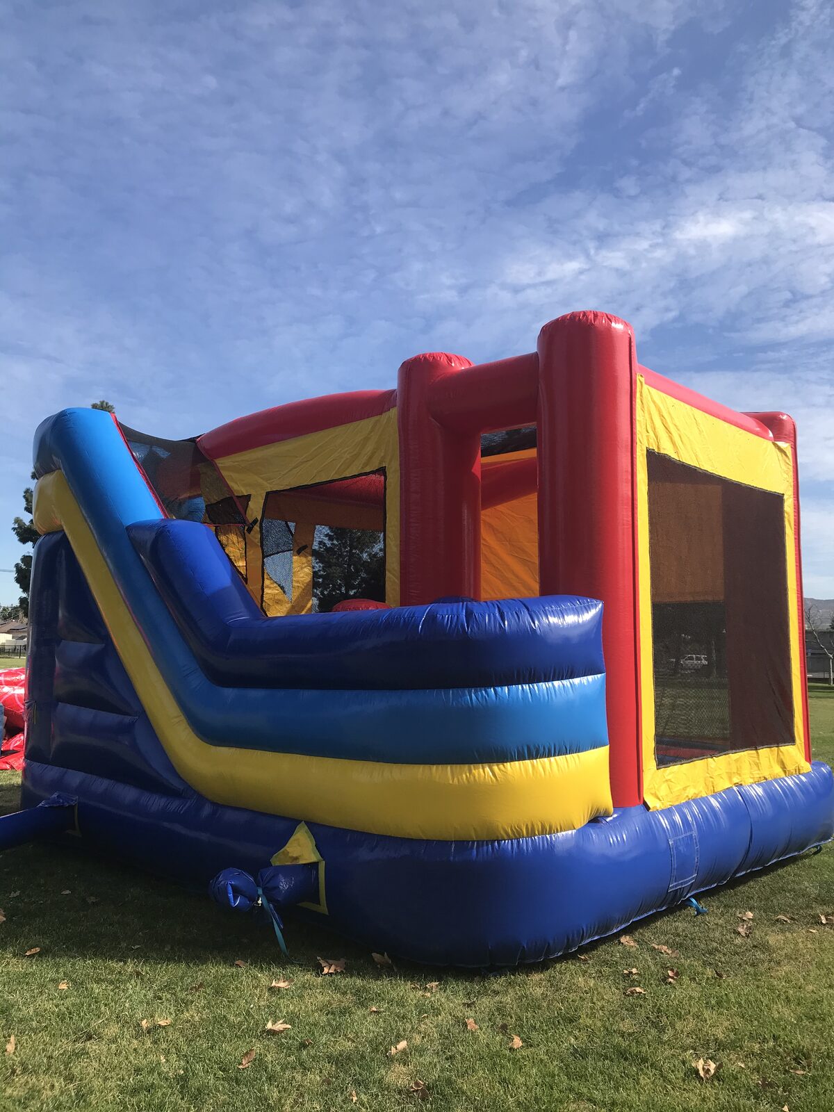 6n1 banner combo bounce house rental in San Diego, wide view of the full unit set up at a San Diego park