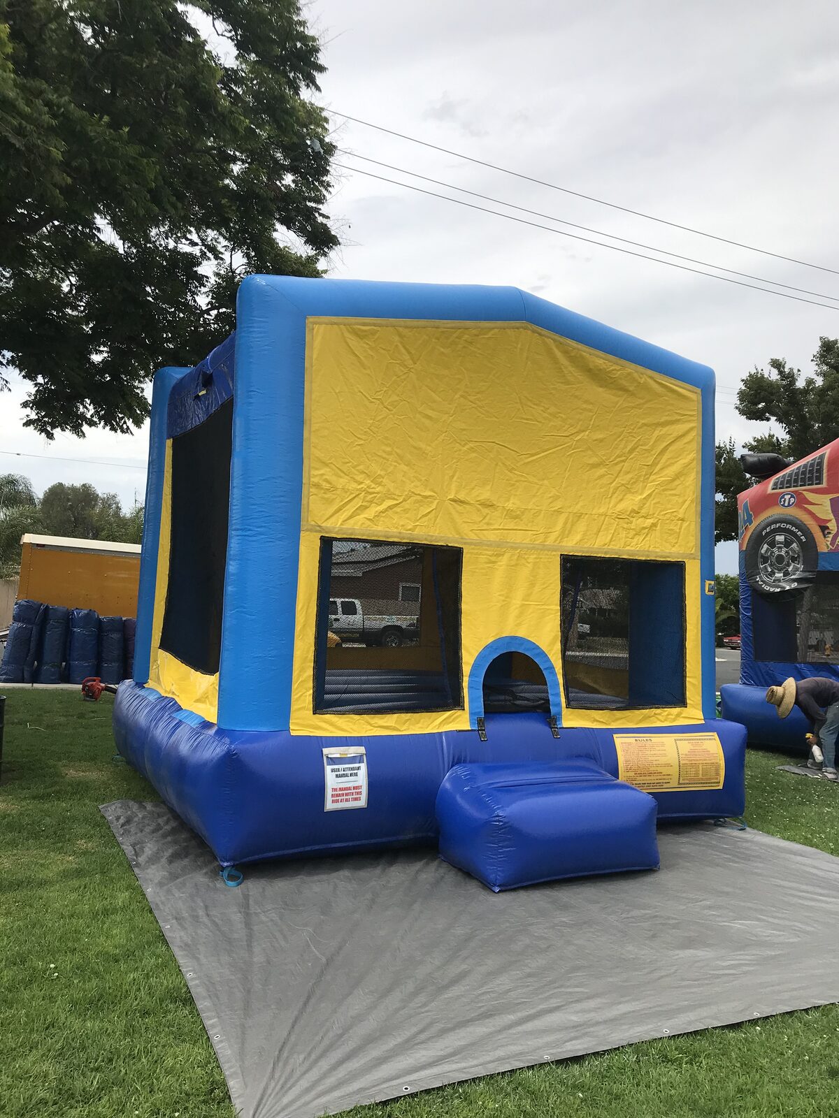 13x13 blue banner bounce house rental in San Diego — side-angled view showing the full yellow banner panel ready for a custom theme