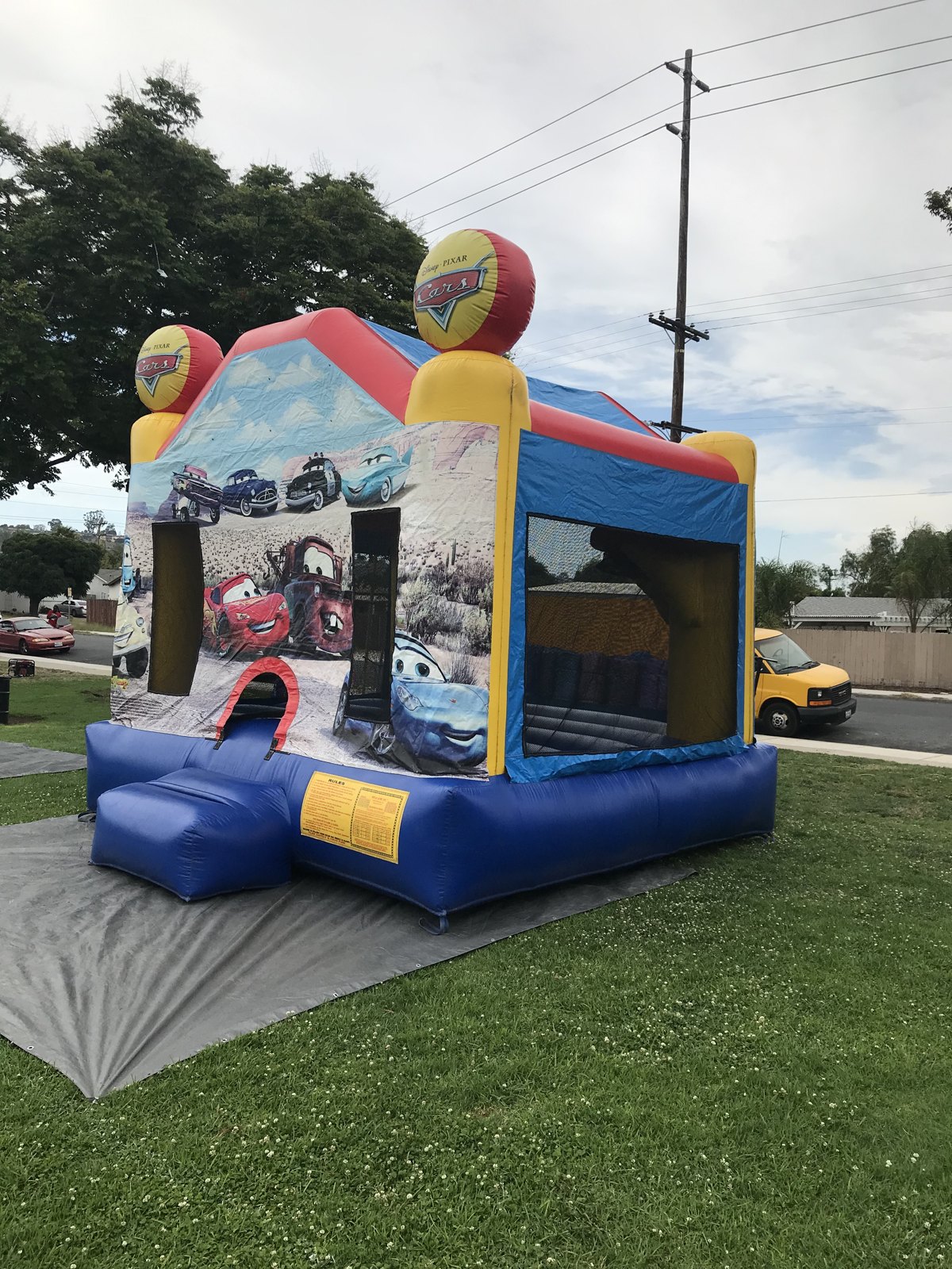13x13 Disney's Cars bounce house rental in San Diego — side-angled setup showing the large mesh safety windows and blue base