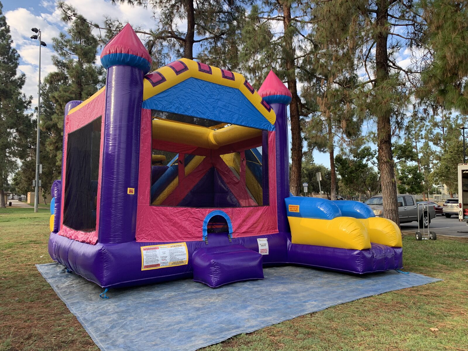 6n1 dream castle combo bounce house rental in San Diego, angled front view of the castle turrets and the blue and yellow slide lane
