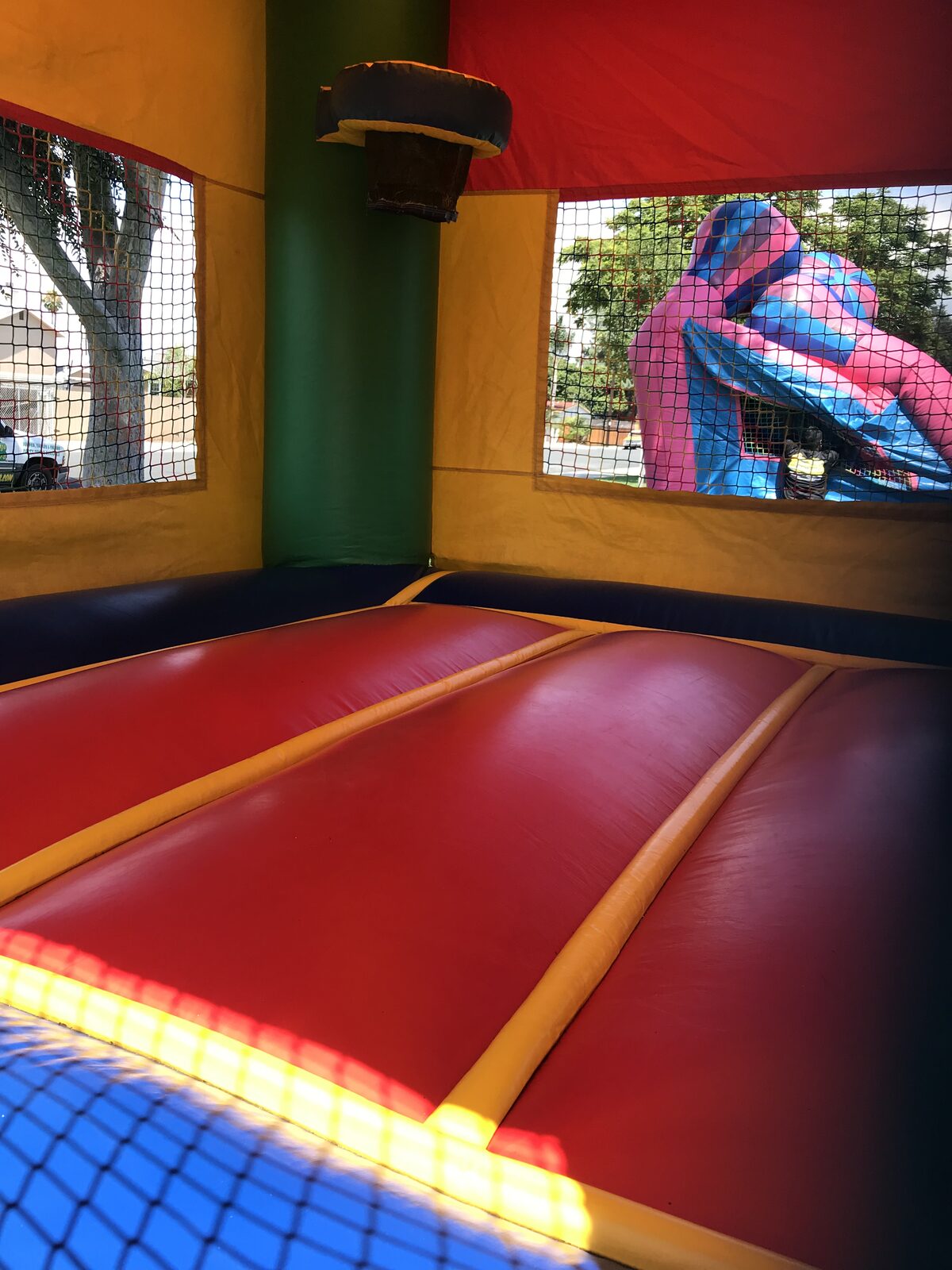 2n1 multi color castle banner combo bounce house rental in San Diego, inside view of the red jump floor with basketball hoop and mesh windows