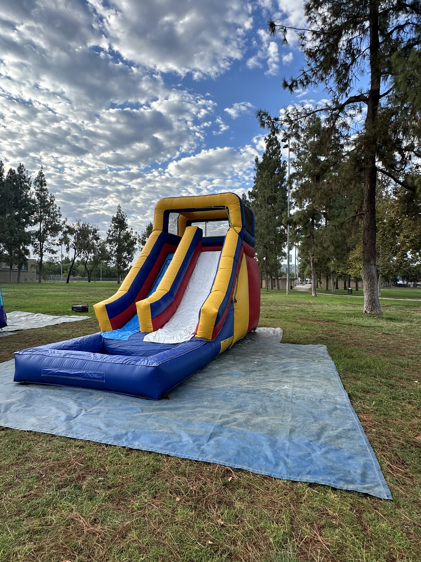 Water slide rental in San Diego, 15ft multi color water slide wide view showing the full footprint on the ground tarp