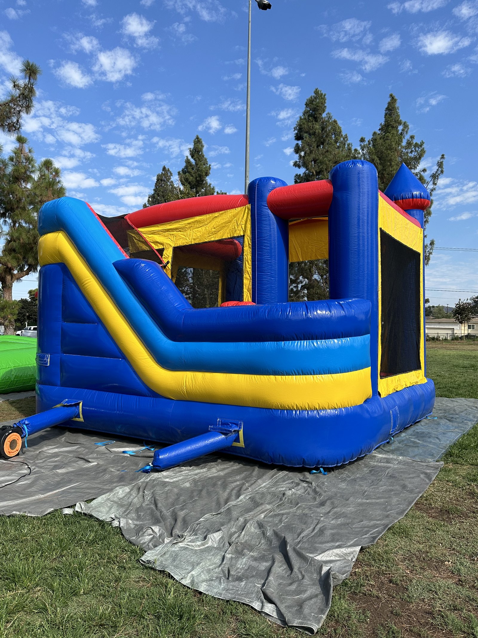 6n1 blue castle combo bounce house rental in San Diego, rear angle of the slide lane with the unit staked to the tarp