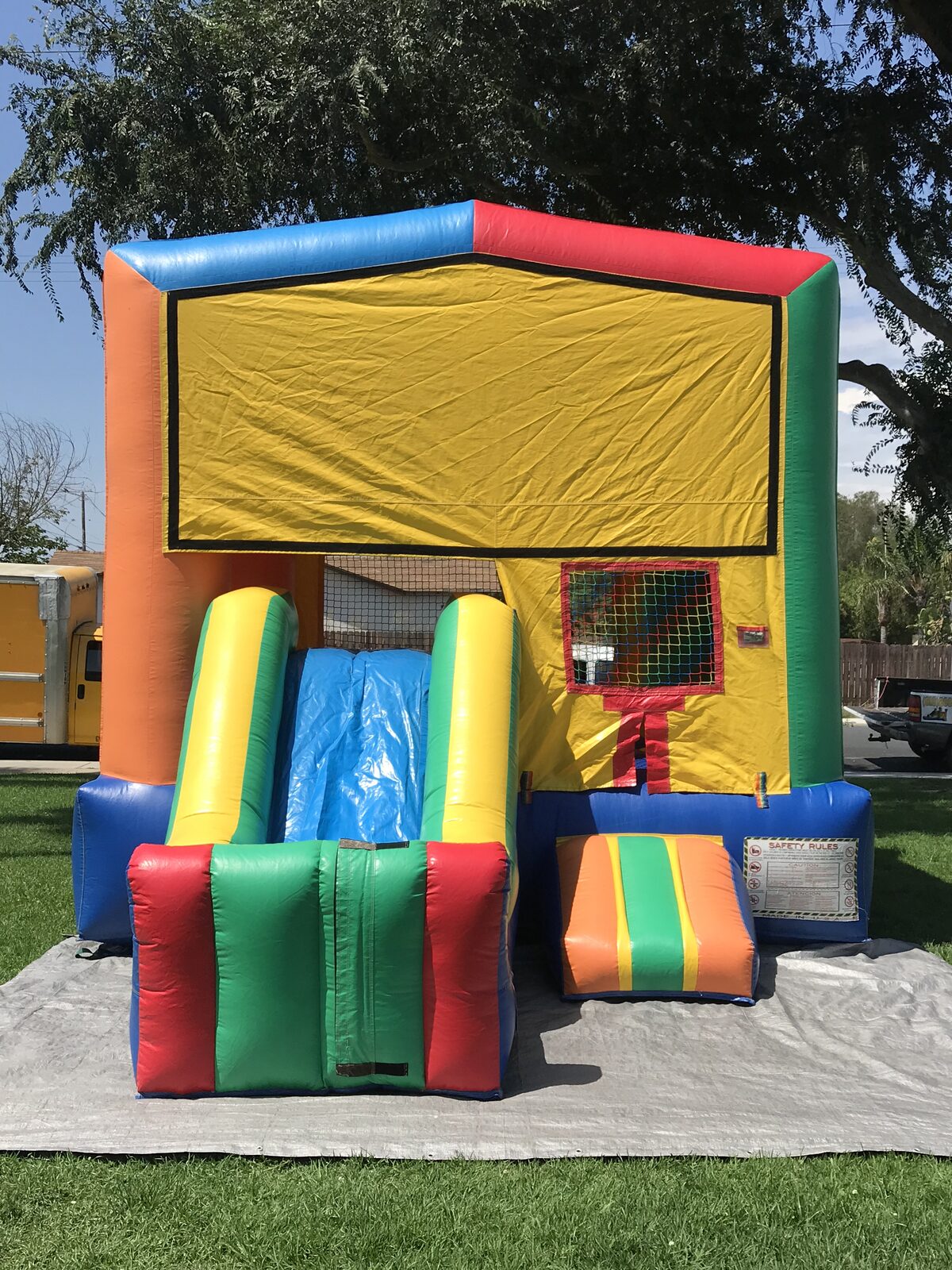 2n1 multi color castle banner combo bounce house rental in San Diego, front view of the yellow banner panel with the blue and yellow slide and striped entry step