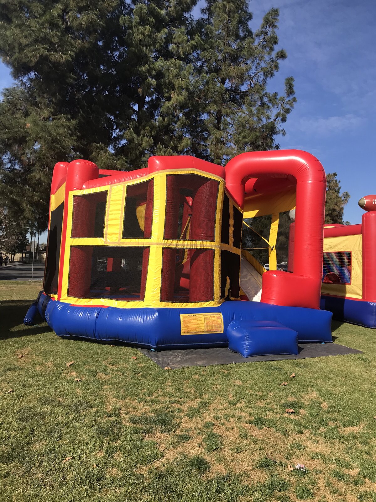 5n1 blue banner combo bounce house rental in San Diego, side view showing the full slide lane and safety rules placard