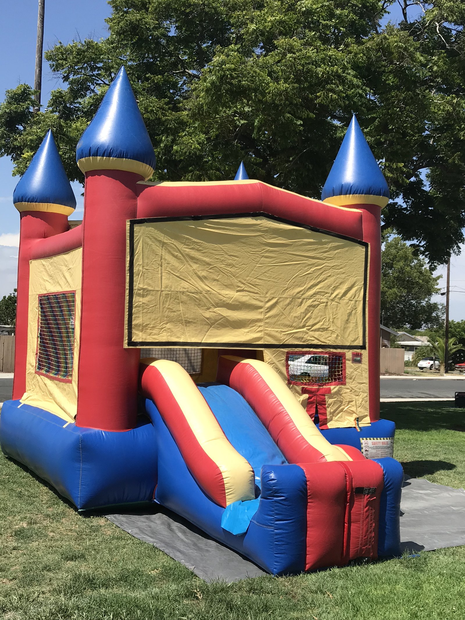 2n1 blue castle combo bounce house rental in San Diego, three-quarter view of the blue side slide and inflatable castle turrets