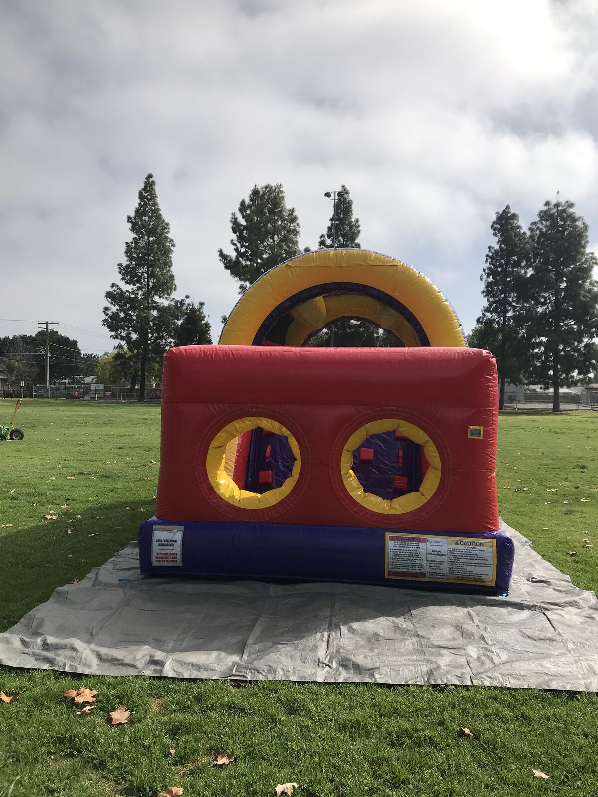 30ft backyard obstacle course rental in San Diego, finish-end view of the red wall with two tunnel openings and safety instruction panels
