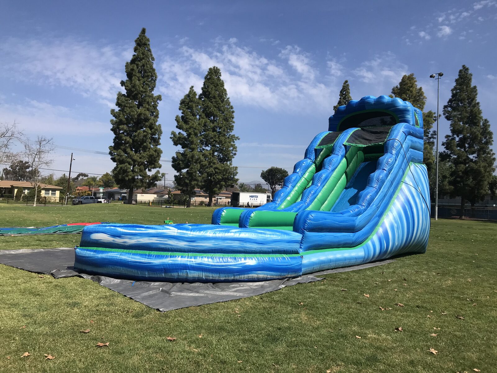 Dry slide rental in San Diego, 20ft green and blue setup side view showing the full slide lane and landing