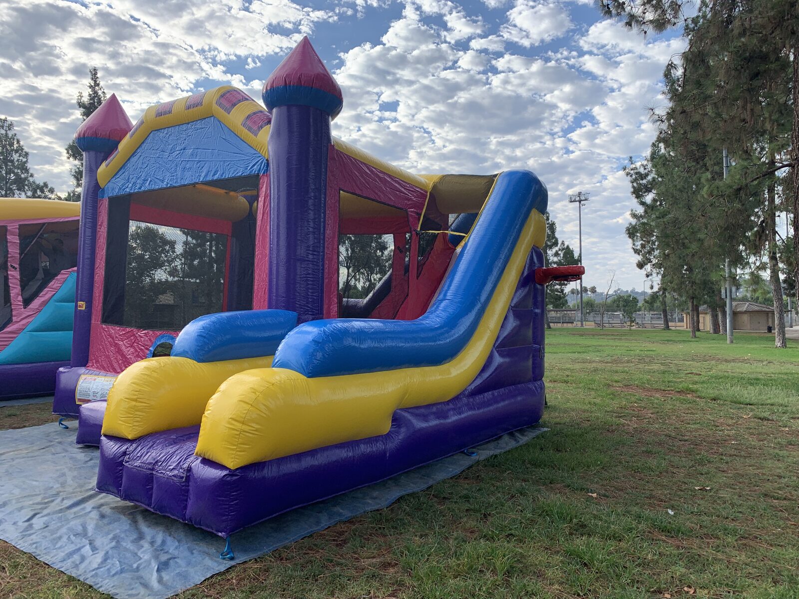 6n1 dream castle combo bounce house rental in San Diego, side view of the full slide run with the safety rules placard on the front
