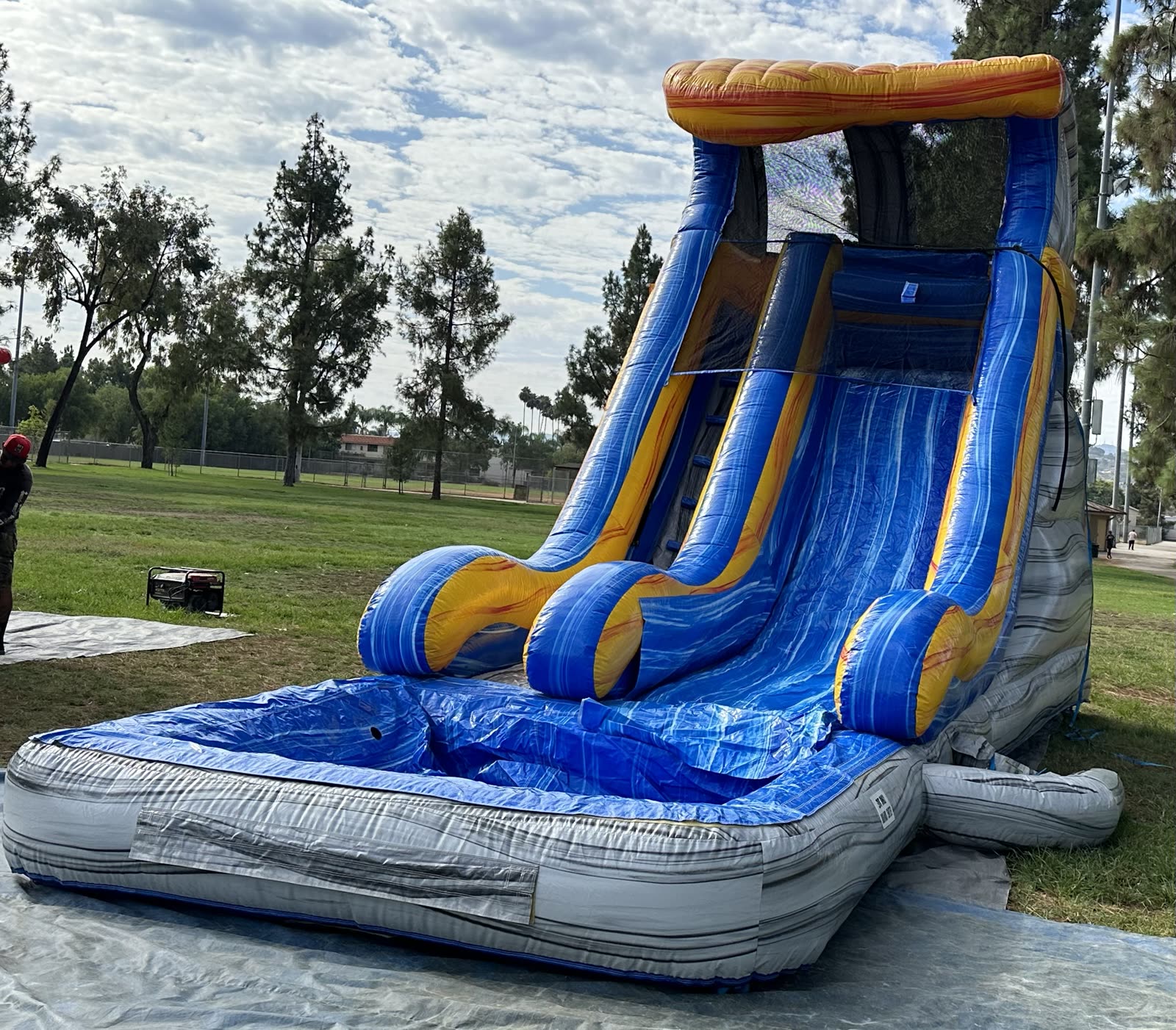 Water slide rental in San Diego, 18ft tidal wave setup angled view on grass with the blower generator set up beside it