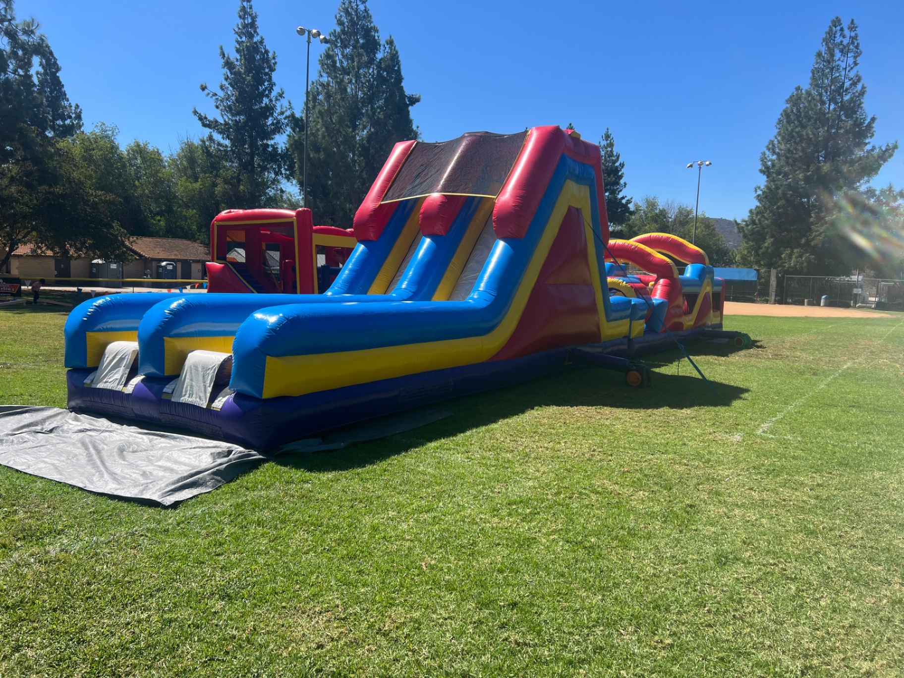 70ft monster obstacle course rental in San Diego, angled view of the slide tower with the obstacle run behind it