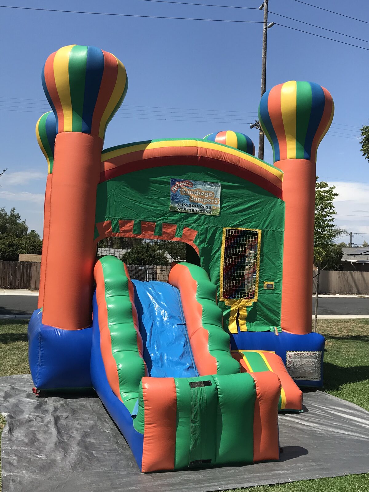 2n1 summer balloon combo bounce house rental in San Diego, front three-quarter view of the green and orange unit with hot air balloon towers and blue slide