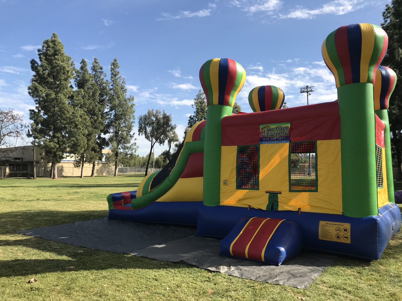 4n1 balloon castle combo bounce house rental in San Diego, three-quarter front view of the striped entry step and mesh windows