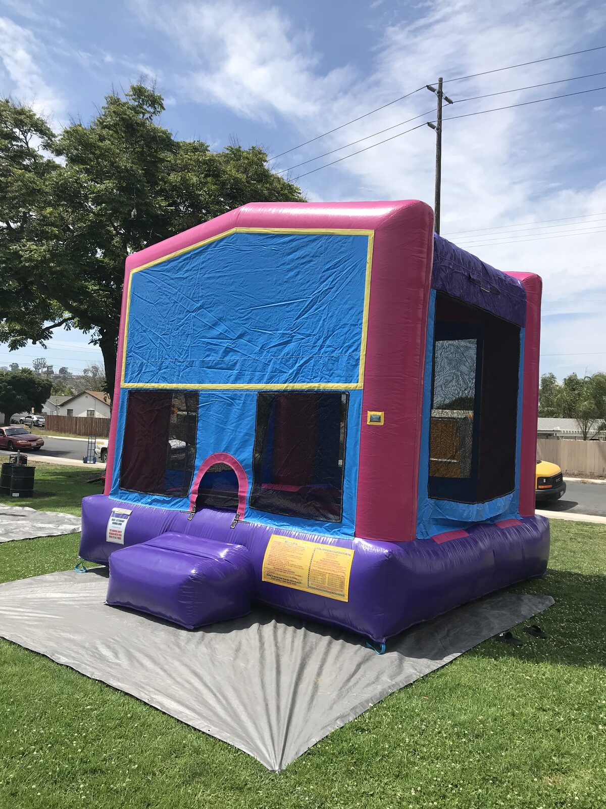 13x13 pink banner bounce house rental in San Diego — angled view with pink frame, purple base, and blank blue banner panel ready for a custom theme
