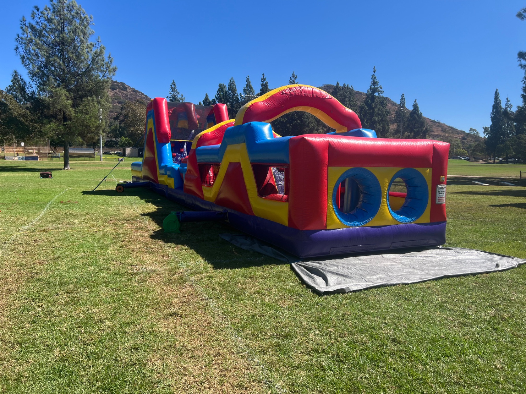 70ft monster obstacle course rental in San Diego, side profile showing pop-up obstacles and the tall slide tower