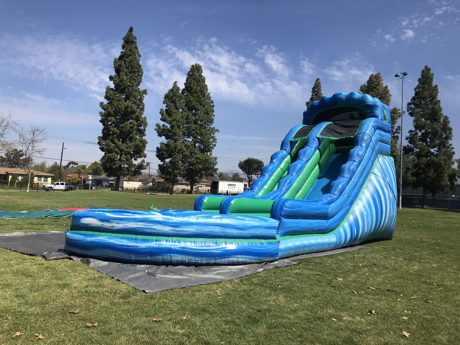 Dry slide rental in San Diego, 20ft green and blue setup wide view on a park lawn under blue skies