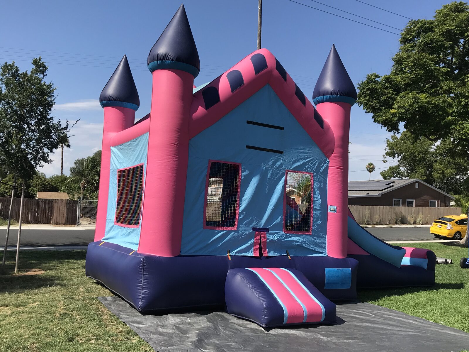 2n1 pink princess combo bounce house rental in San Diego, angled view of the pink turrets, mesh windows, and striped entry step