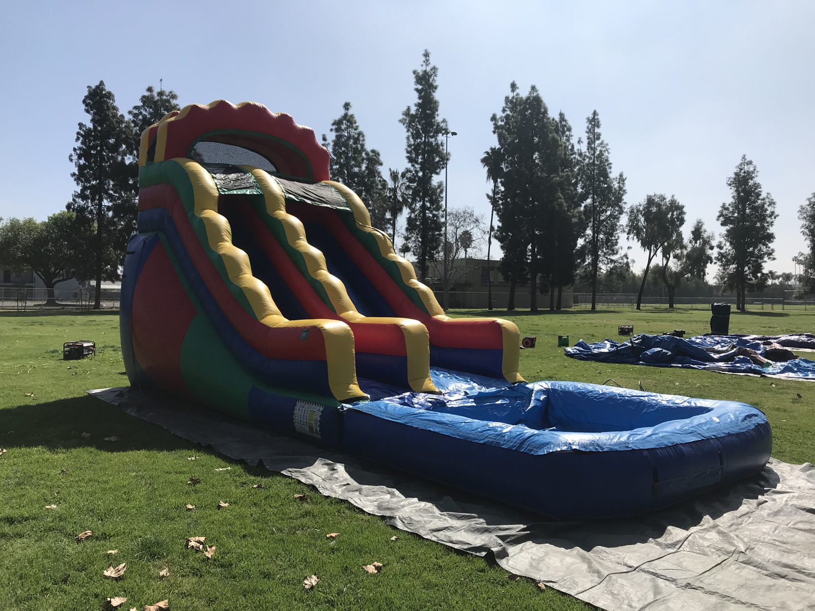 Water slide rental in San Diego, 18ft multi color setup side view showing the red, yellow, green and blue panels and splash pool