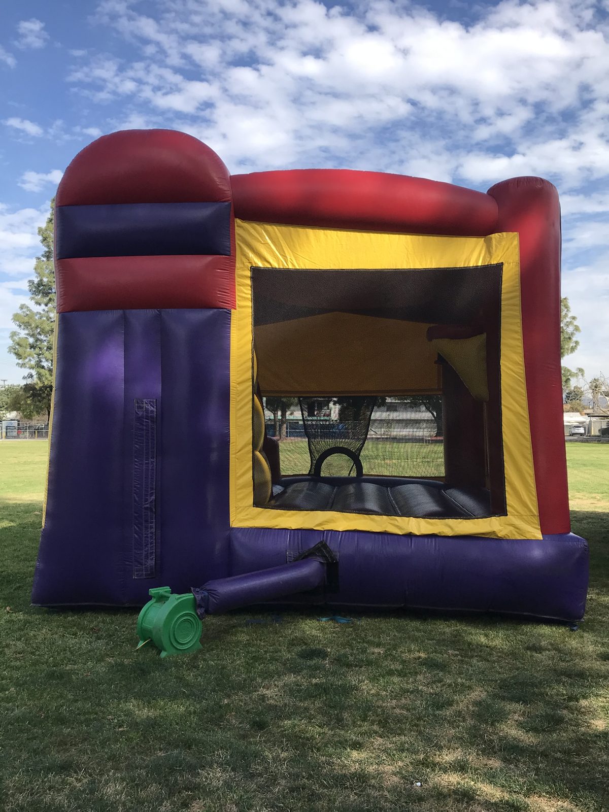 4n1 banner combo bounce house rental in San Diego, back view of the purple slide exit with the blower attached