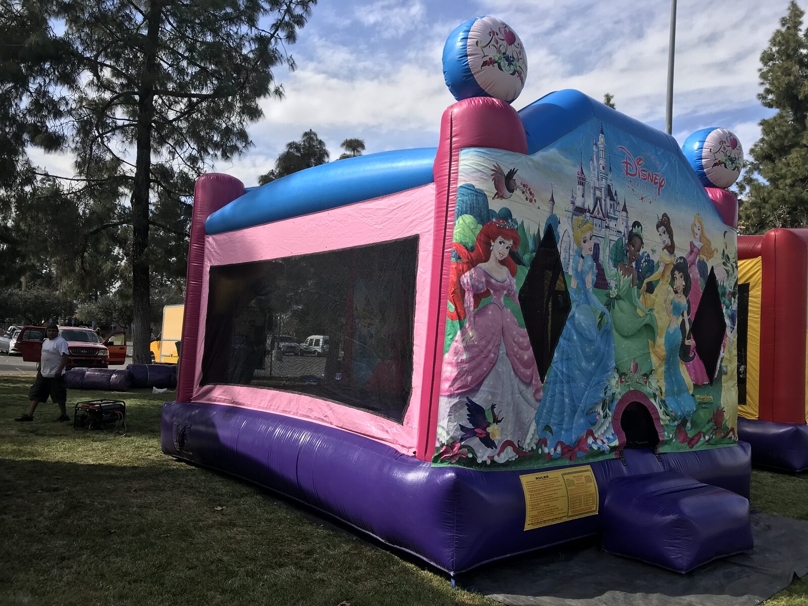 4n1 princess combo bounce house rental in San Diego, wide side view of the pink and purple unit with the blue roof, generator and rules placard