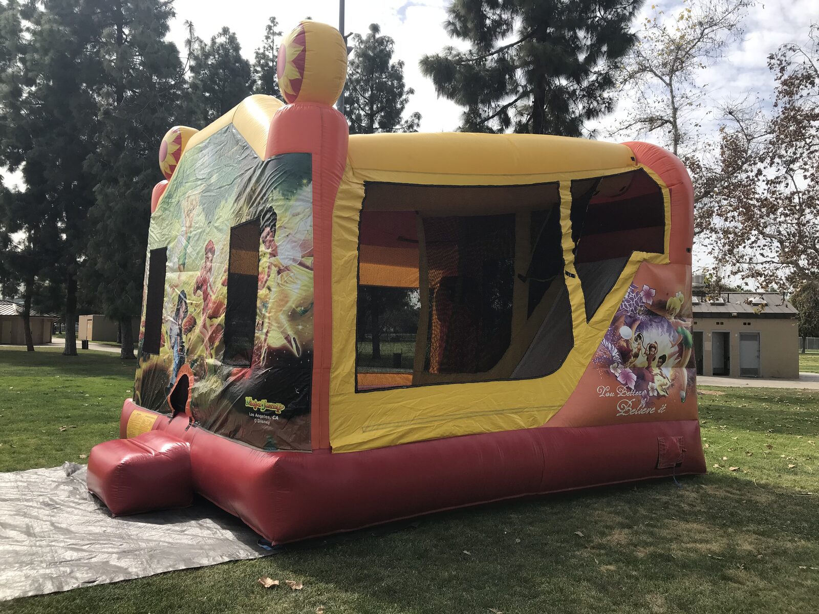 4n1 fairies combo bounce house rental in San Diego, three-quarter view of the Tinker Bell side panel and large mesh windows set up on park grass