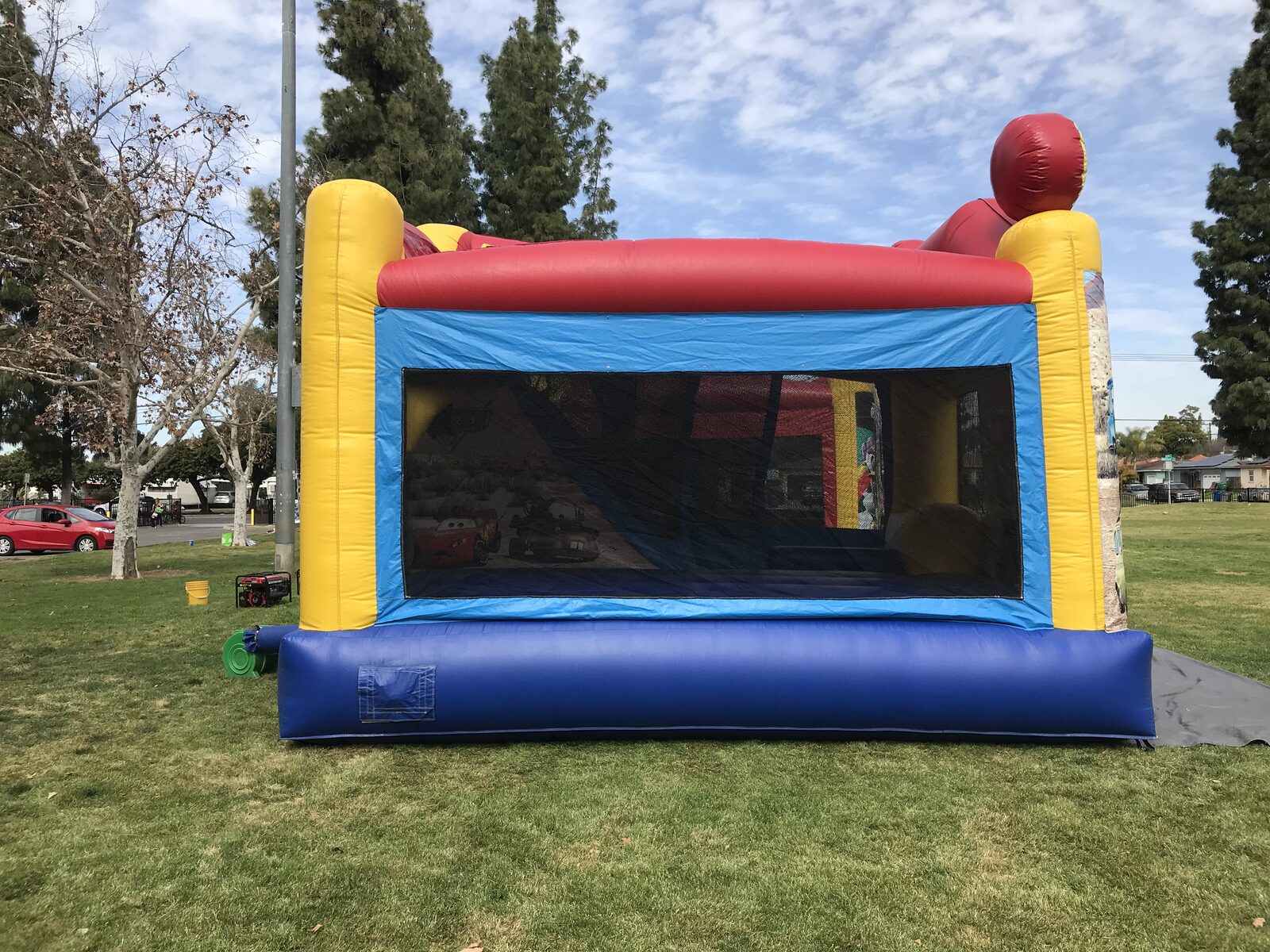 4n1 cars combo bounce house rental in San Diego, wide view of the full unit staked down on park grass