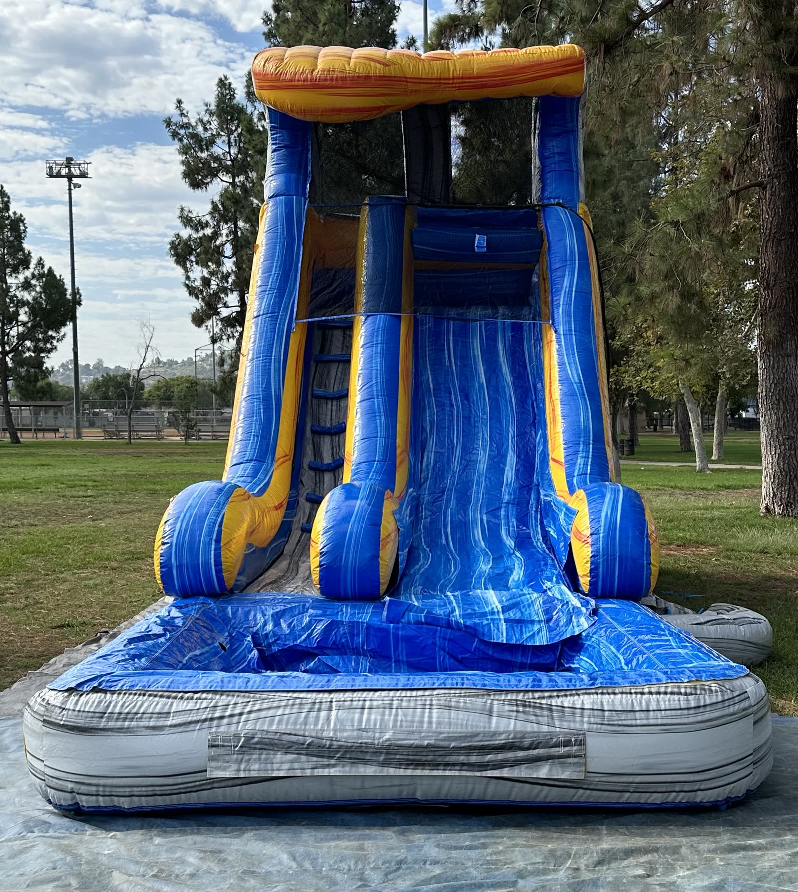 Water slide rental in San Diego, 18ft tidal wave setup front view with blue and yellow marble waves, gray splash pool and shaded canopy top