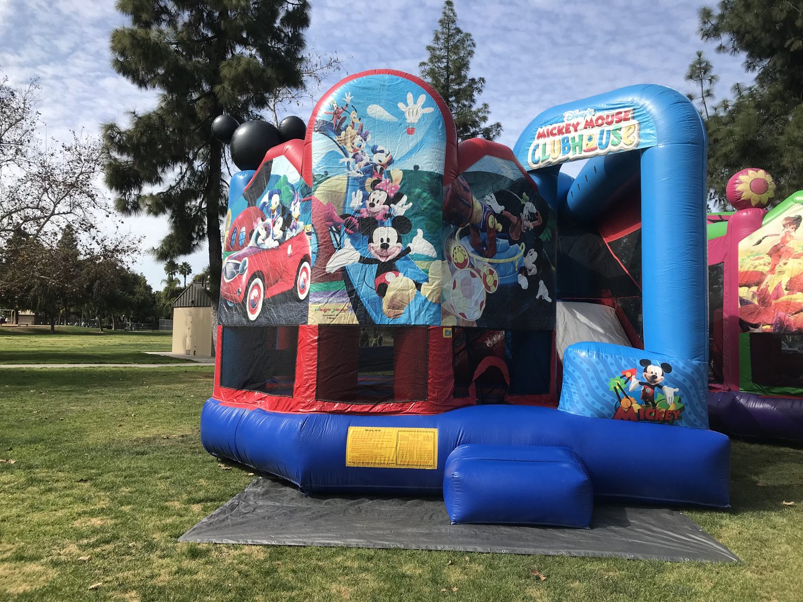 5n1 Mickey combo bounce house rental in San Diego, front view of the Mickey Mouse Clubhouse panels and entry step at a park