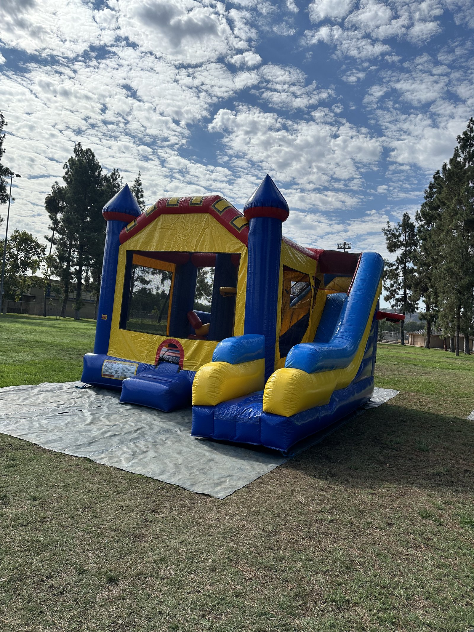 6n1 blue castle combo bounce house rental in San Diego, three-quarter view showing the entry step and full slide run